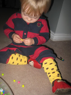Maximilian putting beads on shoelaces